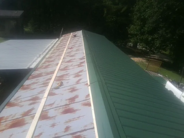 Old rusted panels beside newly installed green metal roofing — Wind Damage Roof Repair by Roofing Brothers in Dawson