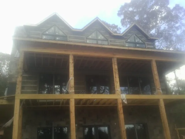 Dormers and porch framing on a large log home under construction — Roof Coating work by our crew in Dawson