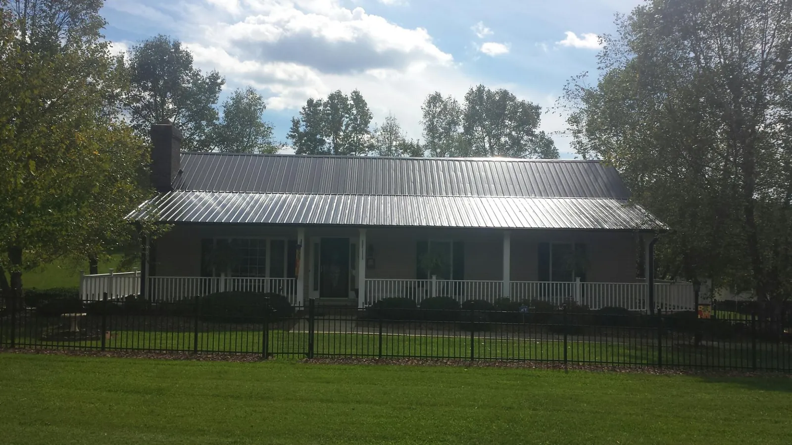 Gray metal roof on a brick ranch with a full width front porch — Gutter Guard Installation work by our crew in Dawson
